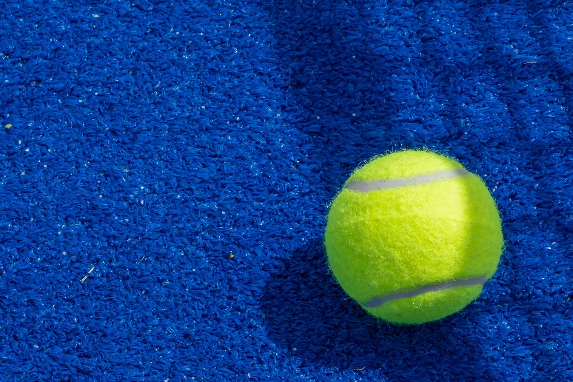 Tennis – Bright yellow tennis ball on blue background